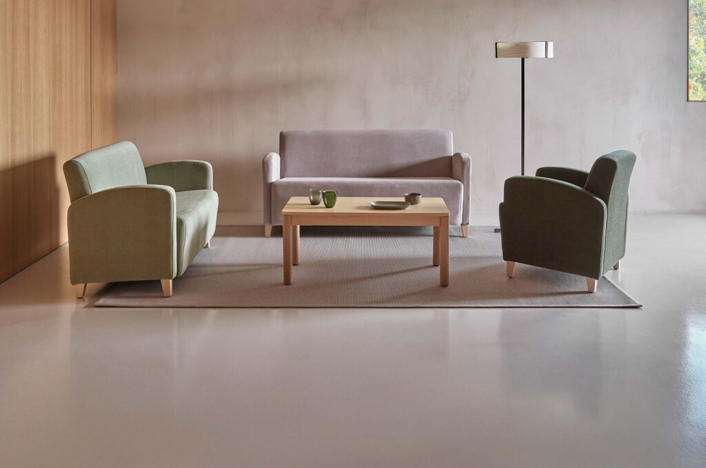 Moderner Lounge‑Bereich mit farblich abgestimmten Sesseln, Sofa und Holztisch in ruhiger, minimalistischer Einrichtung.